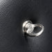 Close-up of a silver metal attachment ring mounted on black padded faux leather surface.