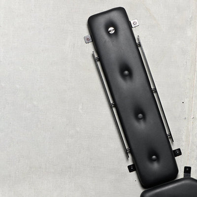 Close-up of black padded arm or leg section of Masters St. Andrew's Cross with metal frame on concrete background.