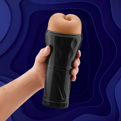 Hand holding a black ergonomic stroker with a flesh-toned, textured sleeve against a dark blue abstract background.