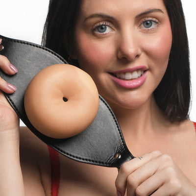 Woman holding a black vegan leather strap gag with a realistic flesh-toned TPE textured front.