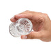 Hand holding a clear, soft, stretchy ball stretcher with textured nubs inside, designed for comfort and stimulation.