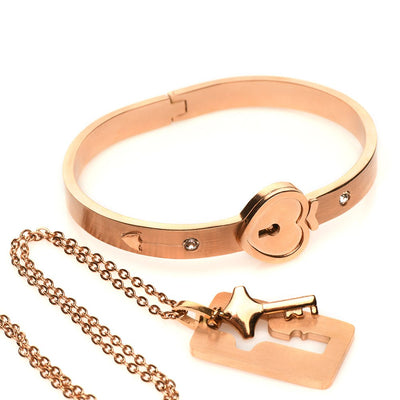 Rose-gold locking bracelet with heart-shaped clasp and matching key necklace on a delicate chain.