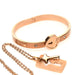 Rose-gold locking bracelet with heart-shaped clasp and matching key necklace on a delicate chain.
