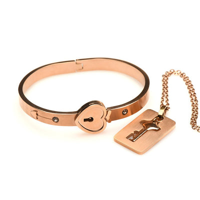 Rose-gold locking bracelet with heart-shaped clasp and matching key necklace on a chain, elegant tungsten steel jewelry set.