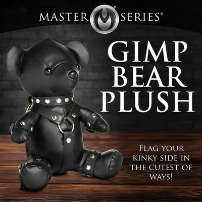 Black vegan leather teddy bear dressed in detailed gimp outfit with studs, sitting on wooden surface against dark background.