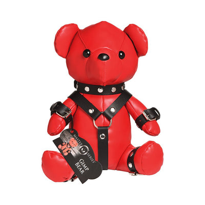 Red vegan leather teddy bear wearing black gimp harness straps and cuffs with metal studs and buckles.
