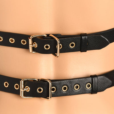 Close-up of black vegan leather harness straps with gold buckles and eyelets on a mannequin.
