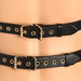 Close-up of black vegan leather harness straps with gold buckles and eyelets on a mannequin.