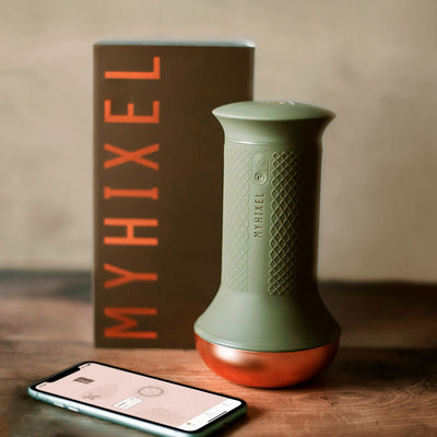 MYHIXEL TR device in olive green with copper base, branded packaging, and smartphone displaying the MYHIXEL app on wooden surface.