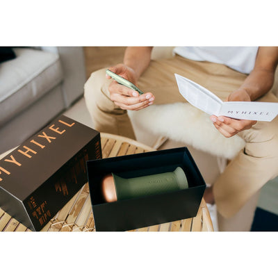 Unboxed MYHIXEL TR device in black packaging on table, with person holding remote and instruction manual nearby.