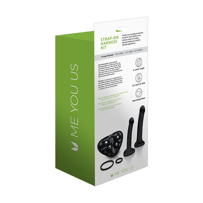 Me You Us strap-on harness kit packaging showing two black dildos, harness base, and interchangeable O-rings on white and green box.