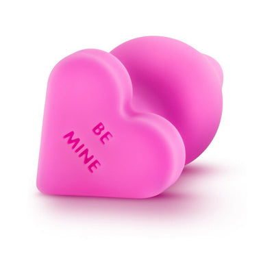 Pink silicone heart-shaped anal plug with "Be Mine" embossed on the base, smooth satin finish.
