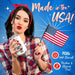 Woman in plaid shirt and red headband holding Naughty Janes Sex Sauce lubricant and American flag with patriotic blue background.