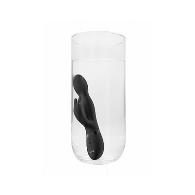 Black Niva Rabbit Vibrator submerged in a clear glass of water demonstrating its waterproof feature.