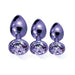 Three purple metal butt plugs with jeweled bases in small, medium, and large sizes displayed on a white background.
