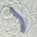 Cornflower blue ergonomic silicone couples massager floating in water with light reflections.