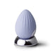 Cornflower blue silicone palm-held massager with textured surface on a reflective silver charging base.