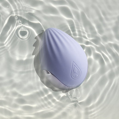 Cornflower blue Niya 4 rechargeable silicone palm held massager floating in water with light reflections.