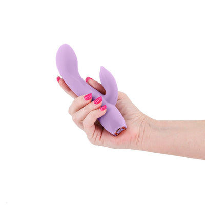 Hand holding a light purple silicone dual-stimulation vibrator with a sleek, curved design.