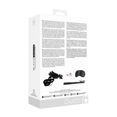 Ouch! Black & White Bondage Belt Restraint System packaging showing included wrist and ankle cuffs, adjustable straps, flogger, dice, and satin mask.