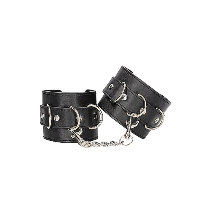 Black and white bonded leather wrist or ankle cuffs with adjustable straps and metal chain connectors.