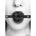 Close-up of a person wearing a black breathable ball gag with bonded leather straps and ventilation holes.