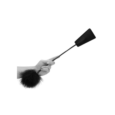 Hand holding a black feather tickler with a bonded leather crop tip for gentle teasing or firm play.