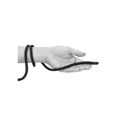 Hand holding a black Japanese silk rope loosely wrapped around the wrist against a white background