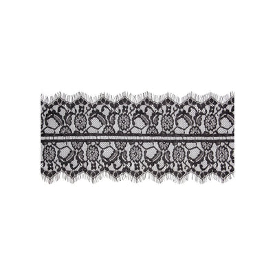 Black and white floral lace fabric with scalloped edges and elastic strap detail on white background.