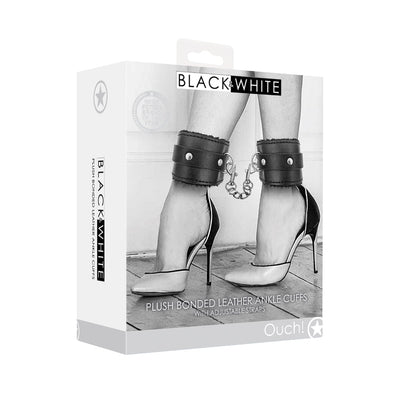 Packaging of Ouch! Black and white plush bonded leather ankle cuffs with adjustable straps shown on model wearing high heels.