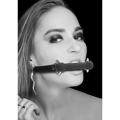 Black and white image of a woman wearing a black silicone bit gag with adjustable bonded leather straps.