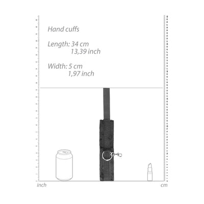 Black and white velcro hand cuff with metal ring and clip, shown with size measurements and comparison to a soda can and lipstick.
