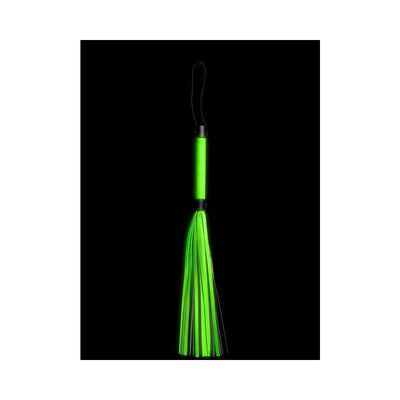 Green glow-in-the-dark flogger with multiple tails and a looped handle against a black background.