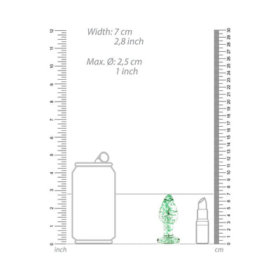 Clear glass butt plug with green glow-in-the-dark speckles shown next to soda can and lipstick for size comparison.