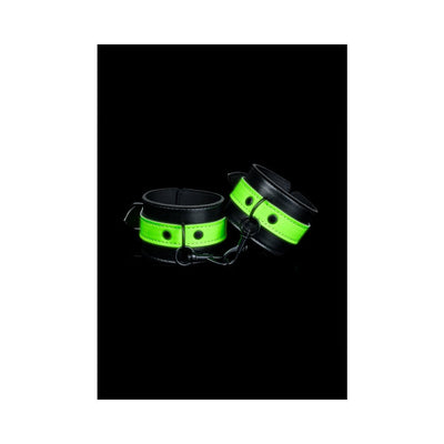 Black and neon green glow-in-the-dark handcuffs with metal chain link on black background.