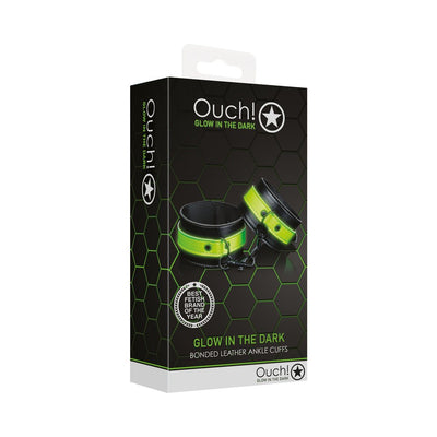 Packaging of Ouch! Glow in the Dark bonded leather ankle cuffs in green with black accents and metal hardware.