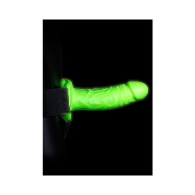 Green glow-in-the-dark realistic 7-inch strap-on harness with adjustable black strap on black background.