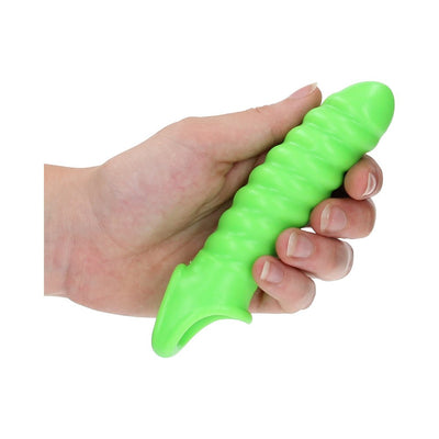 Hand holding a bright green, textured stretchy penis sleeve with a secure ball strap, glow-in-the-dark feature.