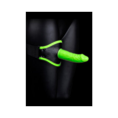 Glow in the dark green silicone dildo attached to an adjustable black thigh harness with neon green trim on a black background.