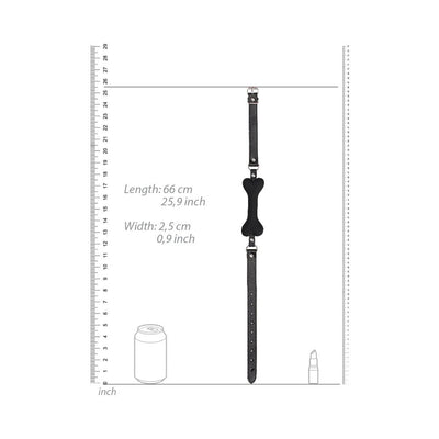 Black silicone bone-shaped gag with adjustable bonded leather straps, shown with measurement scale for size reference.