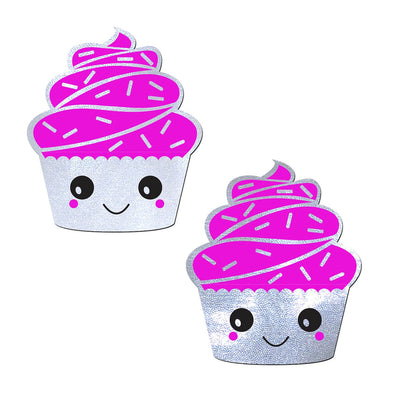 Pair of glittery silver cupcake-shaped nipple pasties with bright pink frosting and smiling faces.