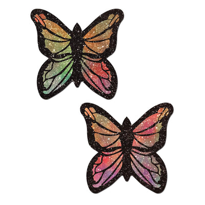 Pair of glittery pastel rainbow butterfly-shaped nipple pasties with black outlines on white background