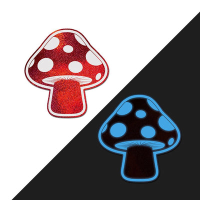 Red and white shiny mushroom-shaped nipple pasties with glow-in-the-dark blue spots on black background.