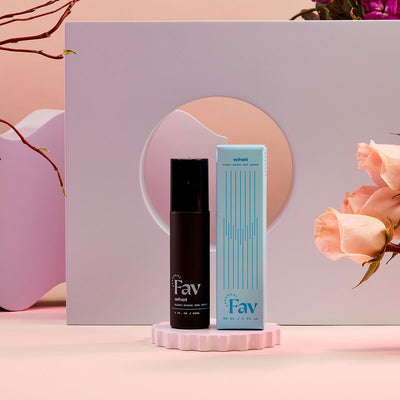 Personal Fav Whet plant-based sex serum bottle and blue packaging displayed with soft pink roses and modern decor background.