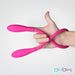 Flexible pink double-ended silicone vibrator held in hand showcasing its bendable design and smooth texture.