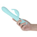 Hand holding a light blue Pillow Talk Lively dual stimulator with textured shaft and curved clitoral attachment.