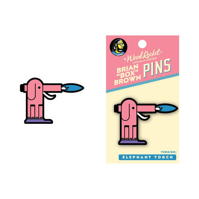 Pink elephant-shaped torch enamel pin with blue flame, displayed on branded backing card by Brian "Box" Brown.