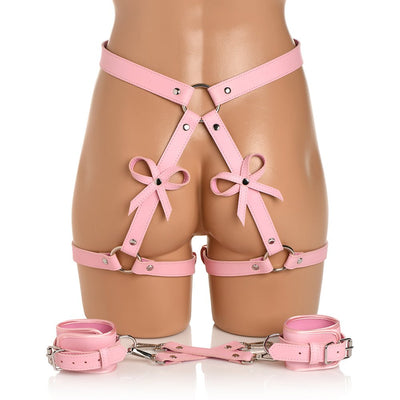 Pink faux leather bondage thigh harness with bows and matching wrist cuffs displayed on a mannequin.