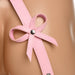 Close-up of pink faux leather thigh harness strap with decorative bow and silver rivet on skin tone background.