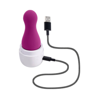 Purple silicone clitoral tapping toy in white USB charging case with attached charging cable on white background.